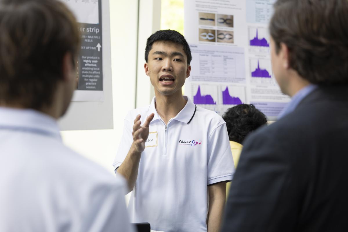 A student presents research findings on a poster to two attendees during a Georgia Tech research and innovation event.